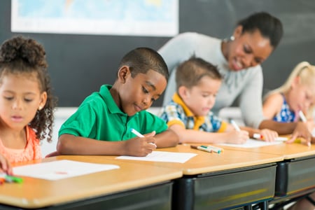 Students writing in class with teacher's guidance