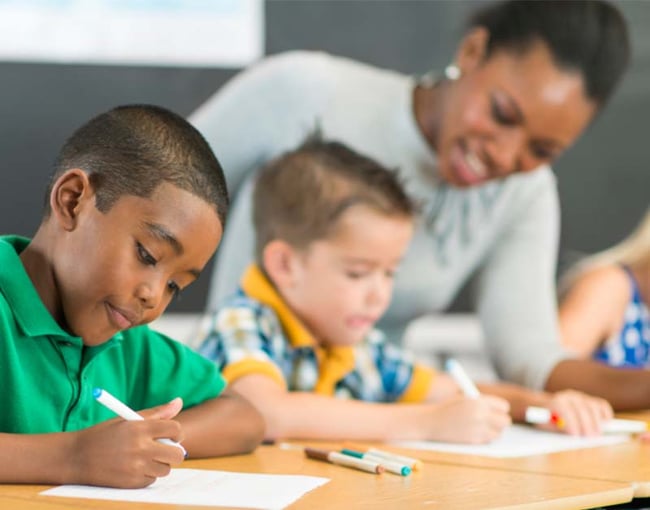 Students writing in class with teachers guidance-2